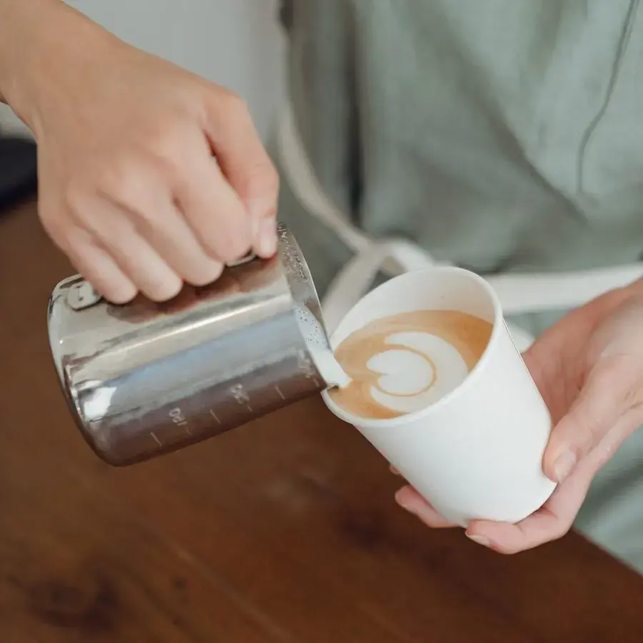 Barista pouring latte art into a takeaway coffee cup at a Perth cafe — Systemly builds automated reservation and feedback systems for cafes and restaurants