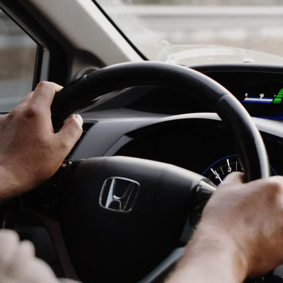 Learner driver's hands on the steering wheel of a car during a Perth driving lesson — Systemly builds automated booking and reminder systems for driving schools