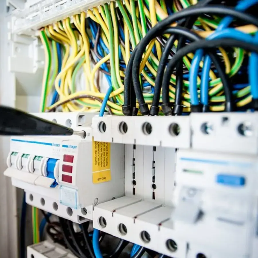 Perth electrician's hand working inside a switchboard with coloured wiring — Systemly builds automated call answering and booking systems for electrical businesses