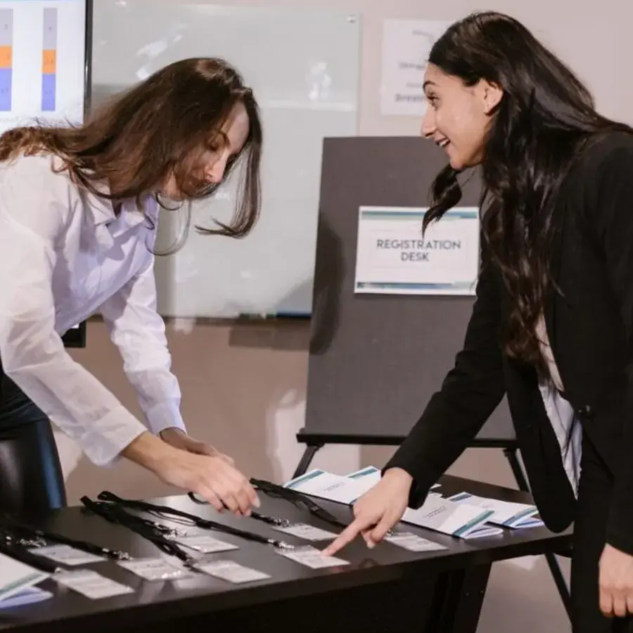 Two event planners coordinating name badges at a registration desk in Perth — Systemly builds automated proposal and vendor coordination systems for event planning businesses