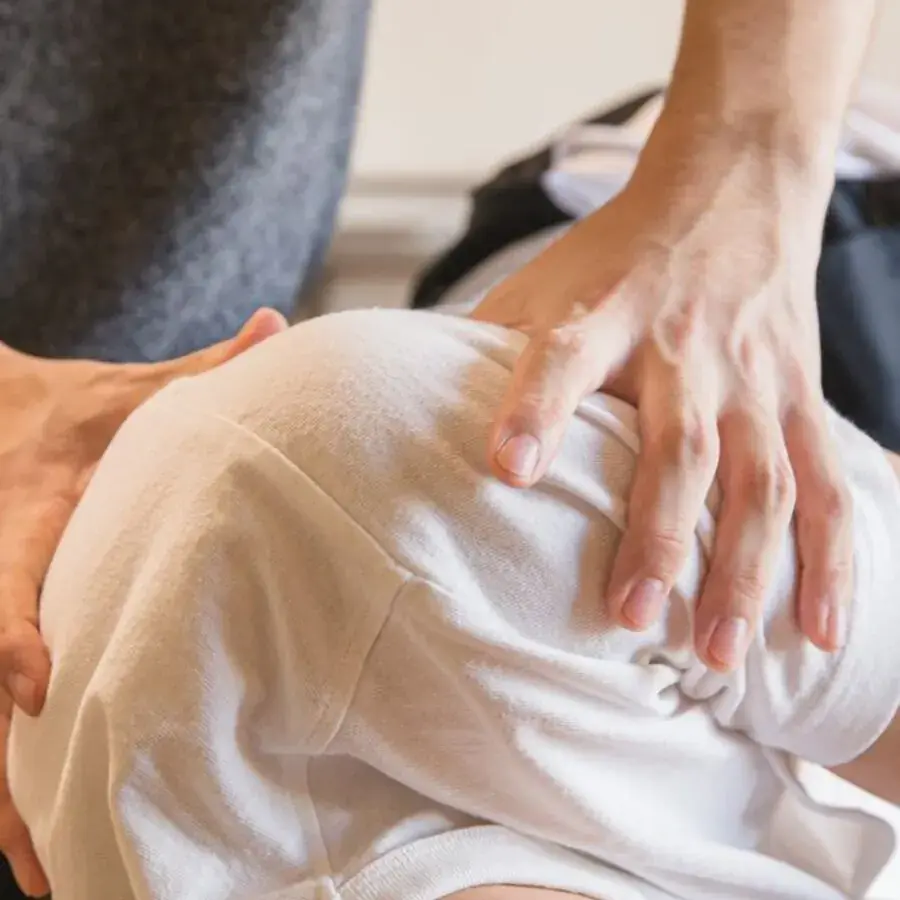 Massage therapist's hands treating a client's shoulder at a Perth clinic — Systemly builds automated booking and rebooking systems for massage therapists