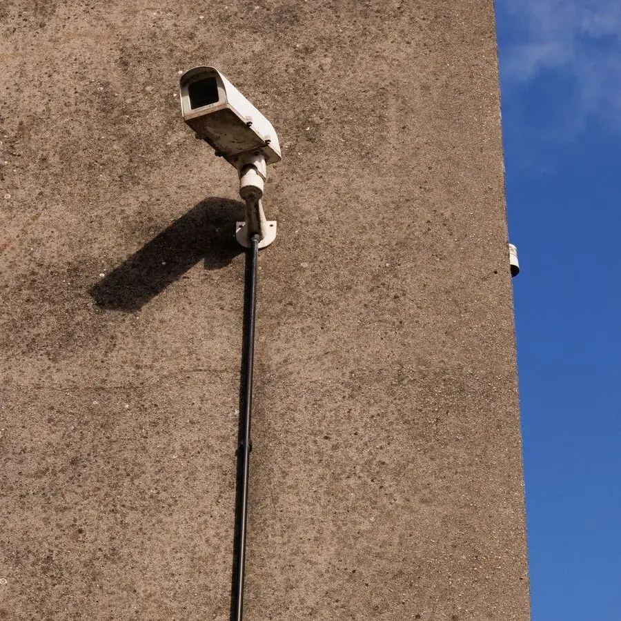 Security camera mounted on a building wall under a clear blue sky in Perth — Systemly builds automated onboarding and scheduling systems for security companies